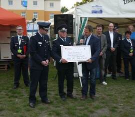 Reinhard Lehmann übergibt einen Check in Höhe von 500€ an die Kreis&shy;jugend&shy;feuerwehr Spree-Neiße.