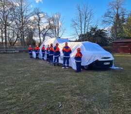 Mitglieder der Jugendfeuerwehren des Amtes Döbern-Land enthüllen ihr neues Mannchaftstransportfahrzeug mit Anhänger.