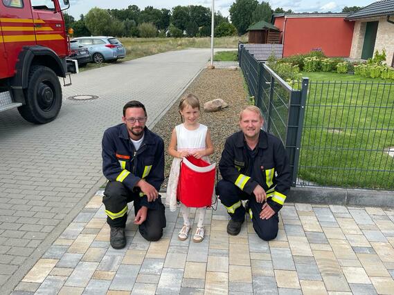 Kinderfeuerwehrwart Marcel Schiemenz und Stellvertretender Jugendfeuerwehrwart Louis Thom überbringen die Geschenke an eine Schulanfängerin